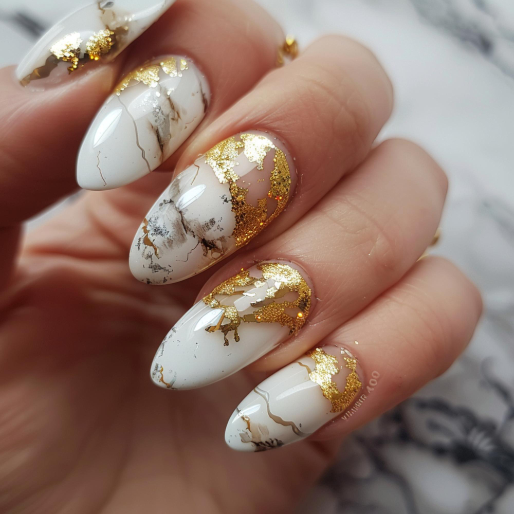 White marble-effect nails with gold foil accents.