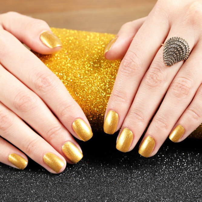Metallic gold polish on short rounded nails.