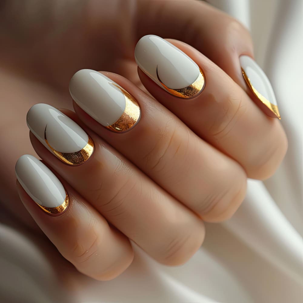 Pale gray oval nails with metallic gold accents.